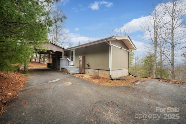 view of side of home with aphalt driveway, crawl space, and an attached carport