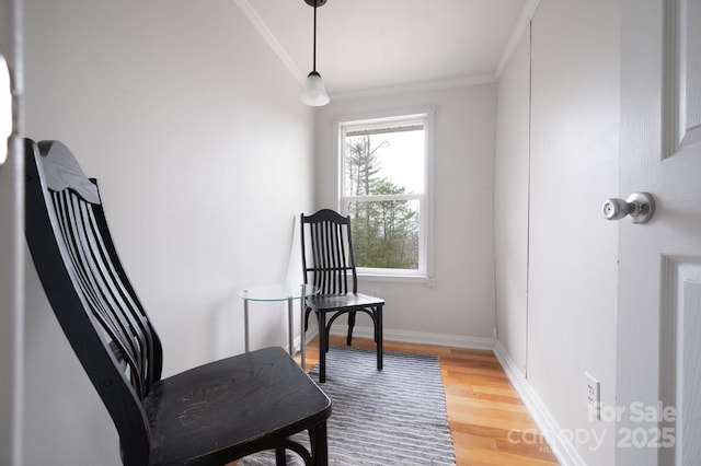 sitting room featuring baseboards, wood finished floors, and crown molding