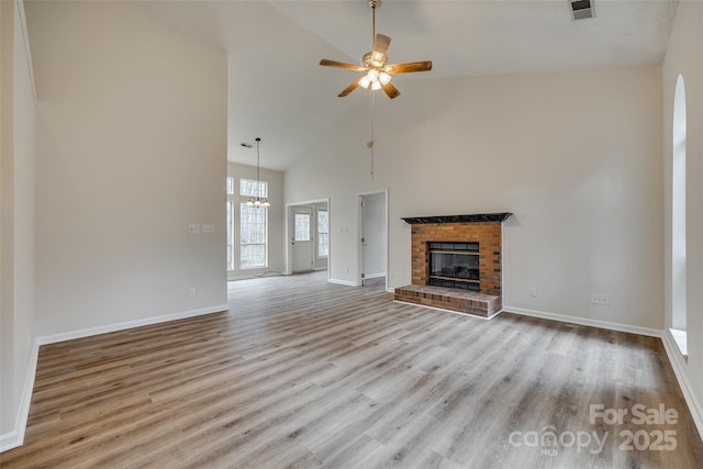 unfurnished living room with ceiling fan, high vaulted ceiling, a fireplace, visible vents, and light wood finished floors