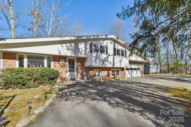 tri-level home with driveway, a garage, and brick siding