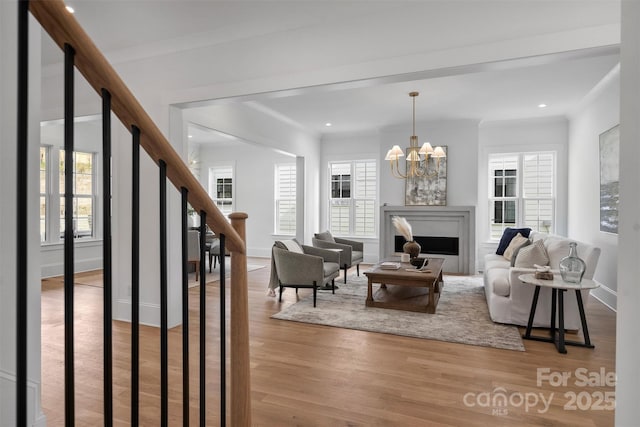 living area featuring a fireplace, stairway, crown molding, and wood finished floors