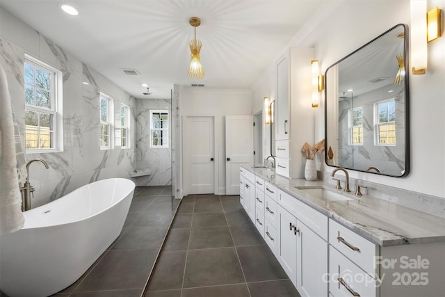 full bathroom featuring a freestanding bath, a marble finish shower, a sink, and visible vents