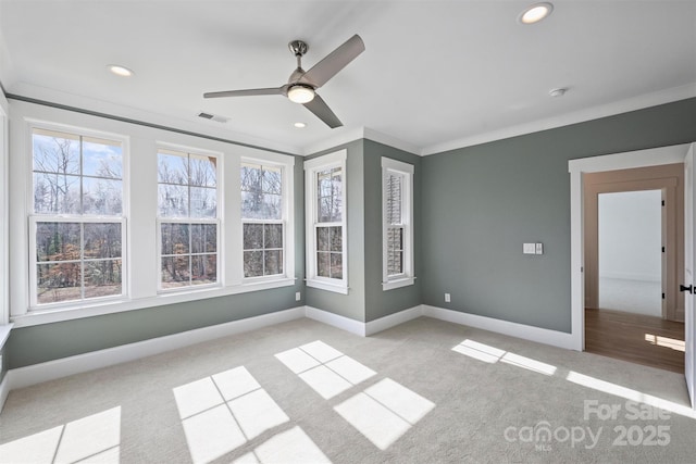 carpeted spare room with ornamental molding, a healthy amount of sunlight, visible vents, and baseboards