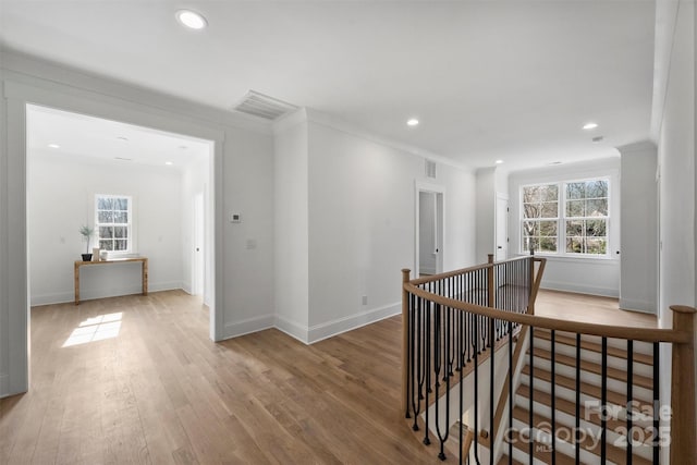 hallway featuring visible vents, a wealth of natural light, wood finished floors, and an upstairs landing