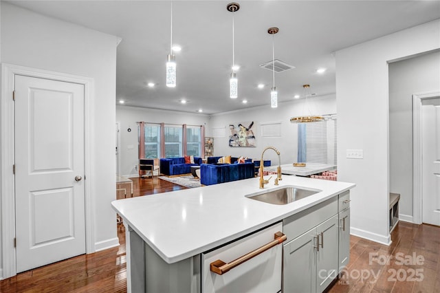 kitchen with dishwasher, light countertops, an island with sink, and a sink