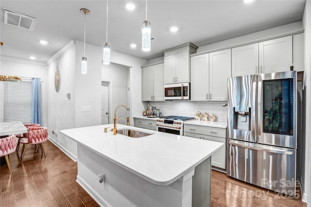 kitchen with a center island with sink, light countertops, hanging light fixtures, visible vents, and white appliances