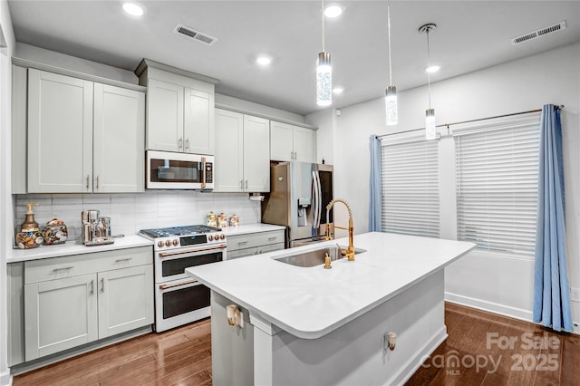 kitchen with white appliances, visible vents, light countertops, pendant lighting, and a sink