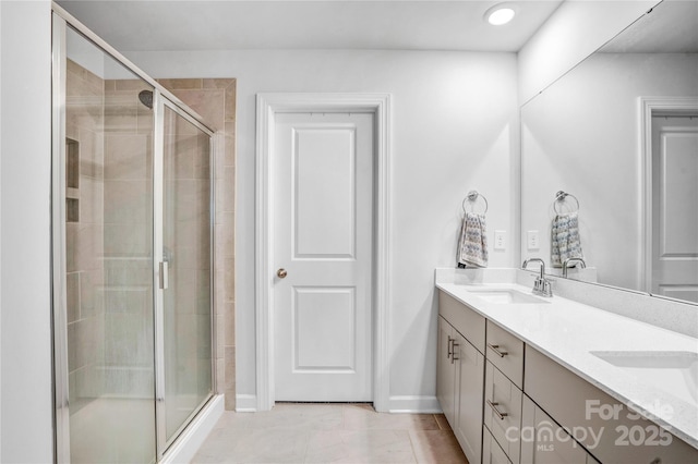 full bathroom featuring a stall shower, a sink, baseboards, and double vanity