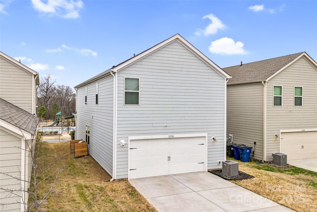 view of property exterior featuring a garage, central AC unit, concrete driveway, and a yard