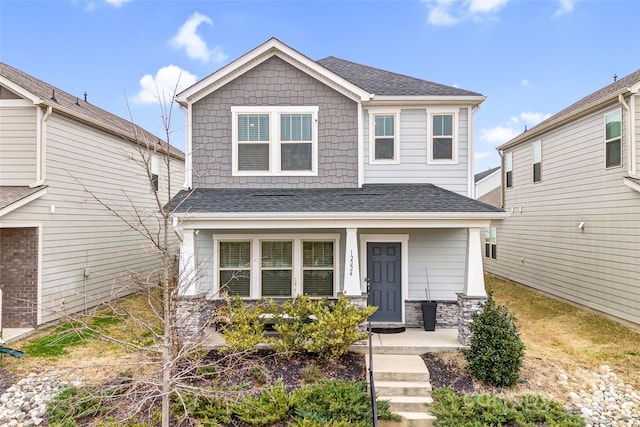 craftsman inspired home with a shingled roof and a porch