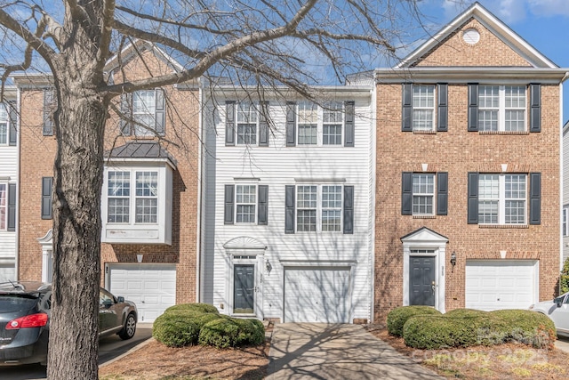 multi unit property featuring driveway, a garage, and brick siding