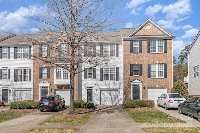 townhome / multi-family property featuring driveway, brick siding, and an attached garage