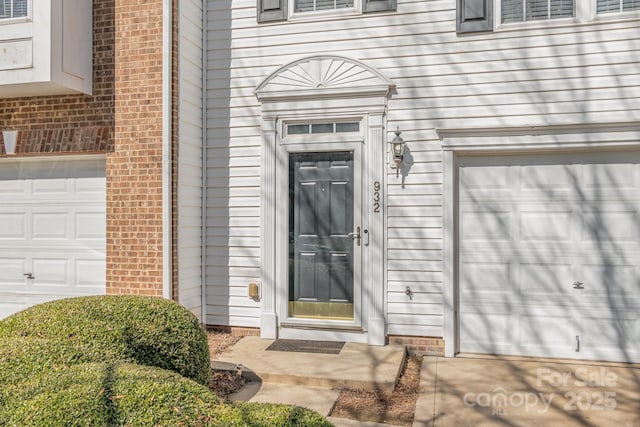 view of exterior entry with brick siding and an attached garage