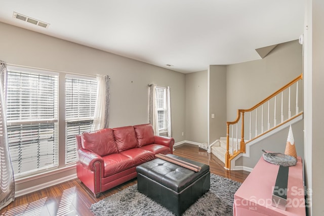 living room with a healthy amount of sunlight, stairway, visible vents, and dark wood finished floors