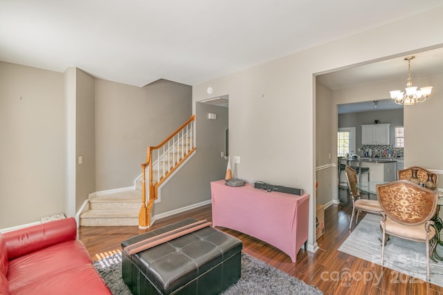 living room with an inviting chandelier, stairs, baseboards, and dark wood-type flooring