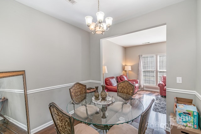 dining area with dark wood-style floors, visible vents, baseboards, and an inviting chandelier