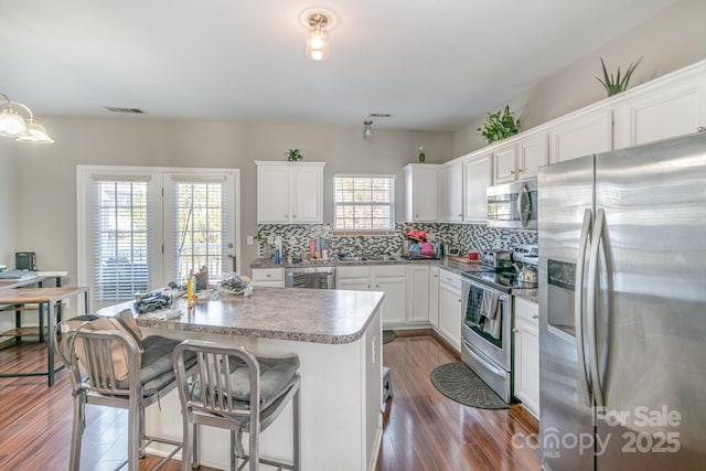 kitchen with a center island, pendant lighting, tasteful backsplash, appliances with stainless steel finishes, and white cabinetry