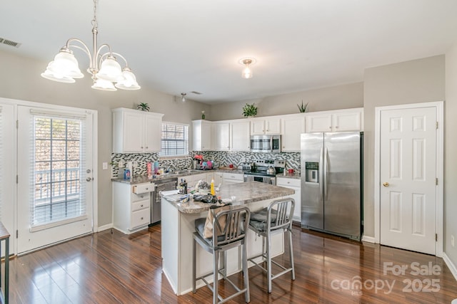 kitchen with a center island, decorative light fixtures, stainless steel appliances, tasteful backsplash, and white cabinets