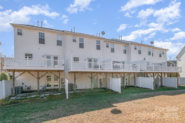 rear view of property with cooling unit, fence, a deck, and a lawn