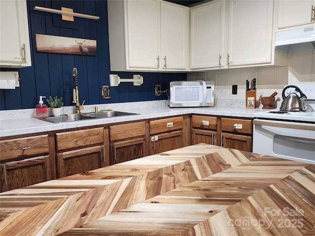 kitchen with sink, white appliances, and white cabinetry