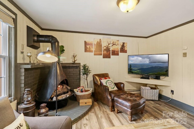 living room with a wood stove, hardwood / wood-style floors, crown molding, and a wealth of natural light