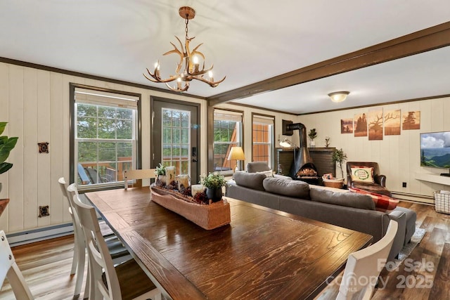 dining room featuring hardwood / wood-style floors, an inviting chandelier, a baseboard heating unit, and ornamental molding