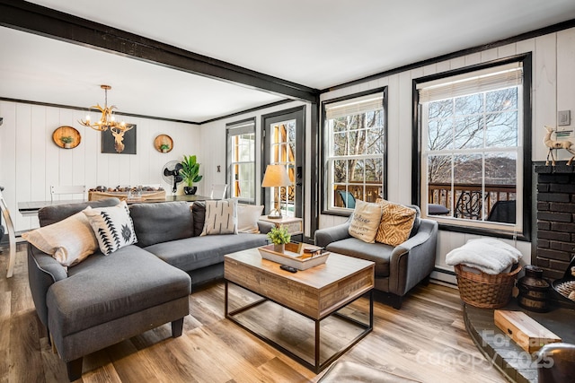 living room featuring an inviting chandelier, light wood-style flooring, baseboard heating, and a wealth of natural light