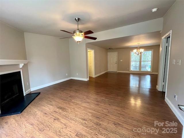 unfurnished living room with baseboards, a fireplace with raised hearth, wood finished floors, and ceiling fan with notable chandelier