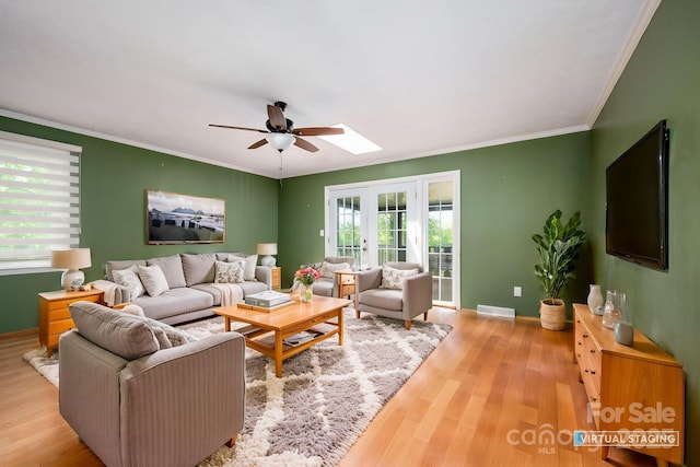 living area featuring wood finished floors, ceiling fan, ornamental molding, and baseboards