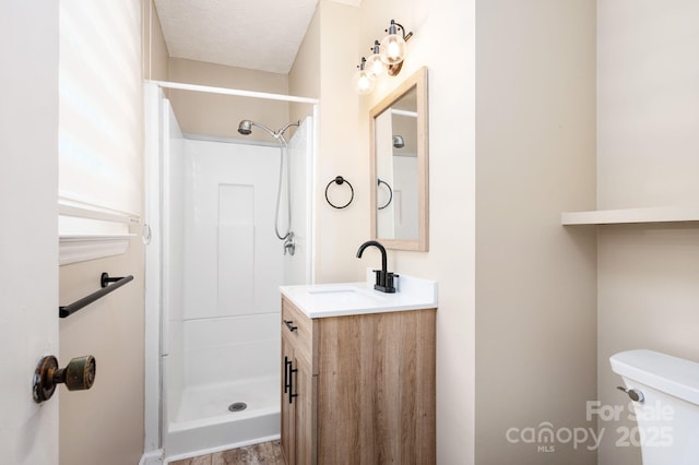 bathroom featuring toilet, vanity, and a stall shower