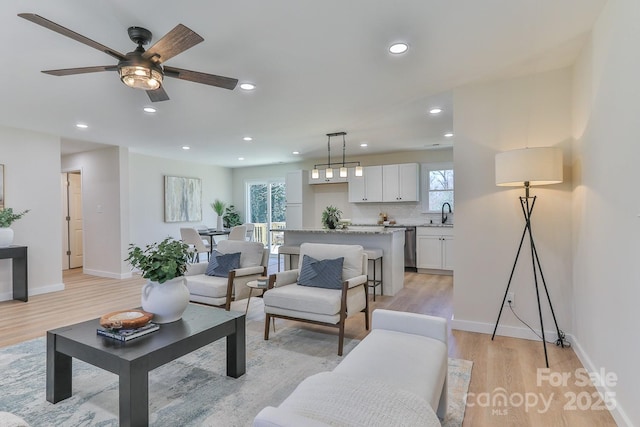 living area with light wood-style floors, baseboards, and recessed lighting