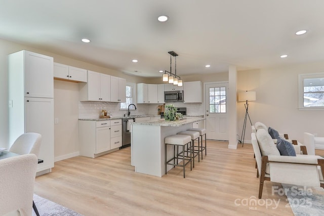 kitchen with a breakfast bar, white cabinetry, stainless steel appliances, and a sink