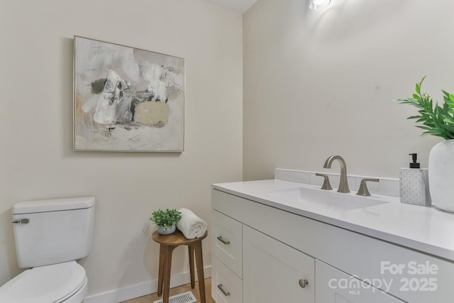 bathroom with toilet, baseboards, and vanity