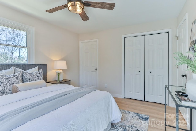 bedroom with baseboards, light wood-style flooring, a ceiling fan, and a closet