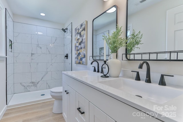 bathroom with double vanity, wood finished floors, a sink, and toilet