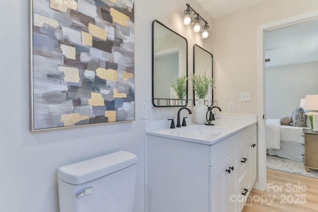 bathroom with wood finished floors, vanity, toilet, and ensuite bathroom