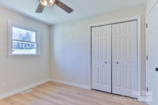 unfurnished bedroom featuring ceiling fan, visible vents, baseboards, a closet, and light wood finished floors