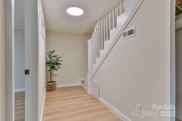 interior space with light wood-type flooring, stairway, baseboards, and visible vents