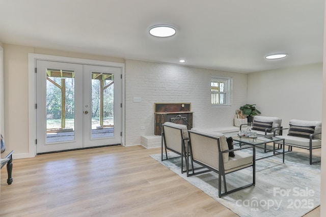 interior space featuring brick wall, wood finished floors, baseboards, french doors, and a brick fireplace