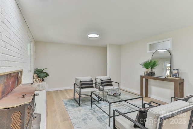 living area with light wood finished floors, a fireplace, and baseboards