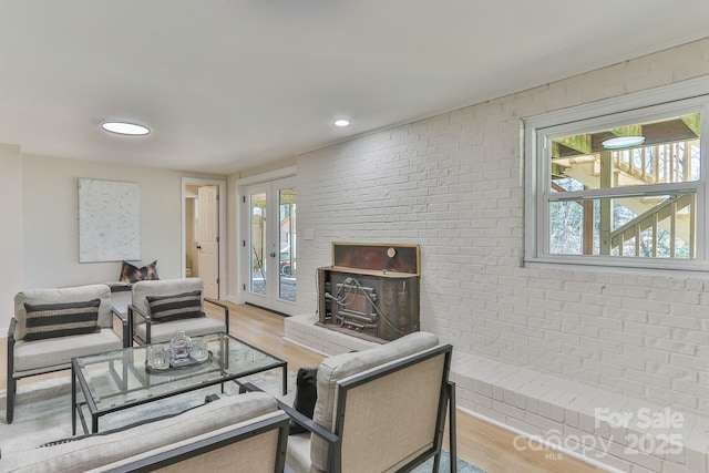 living area featuring recessed lighting, brick wall, wood finished floors, and french doors