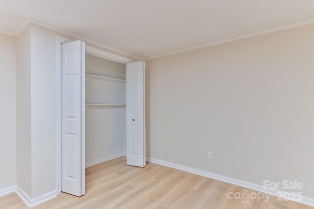 unfurnished bedroom with ornamental molding, light wood-type flooring, a closet, and baseboards