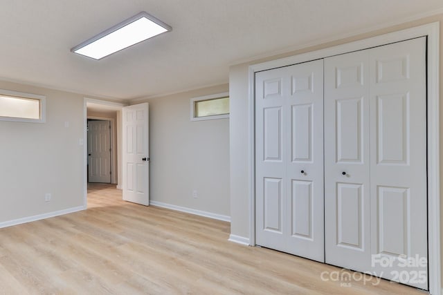 unfurnished bedroom featuring a closet, light wood-style flooring, and baseboards