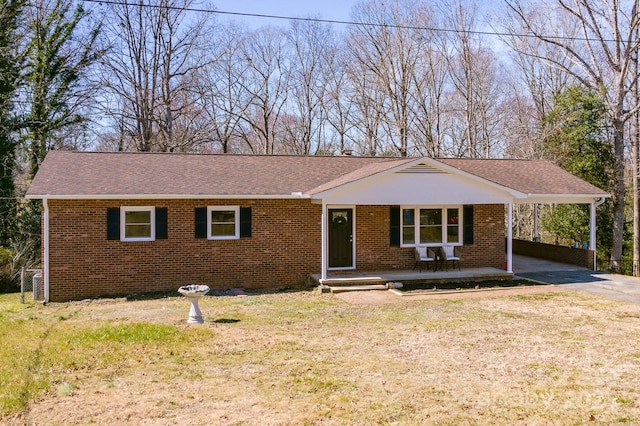 single story home with driveway, a shingled roof, a front lawn, a porch, and brick siding