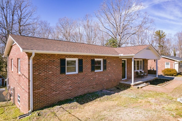 ranch-style house with a shingled roof, a front yard, and brick siding