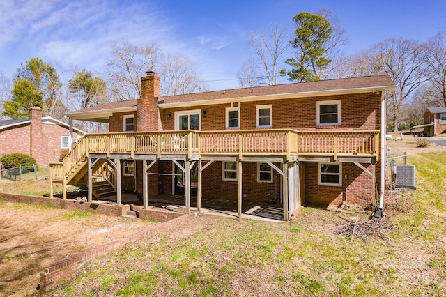 rear view of house featuring a deck, central AC, brick siding, stairs, and a chimney