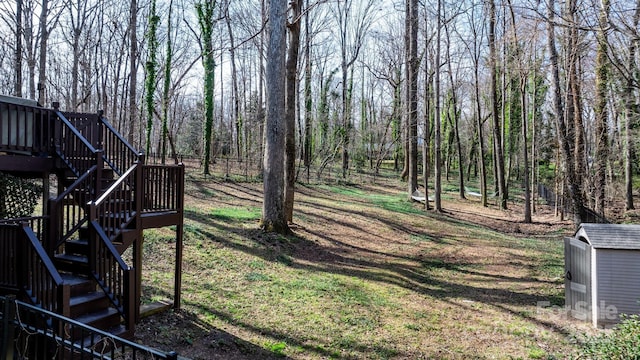 view of yard with a deck, an outdoor structure, stairs, and a shed