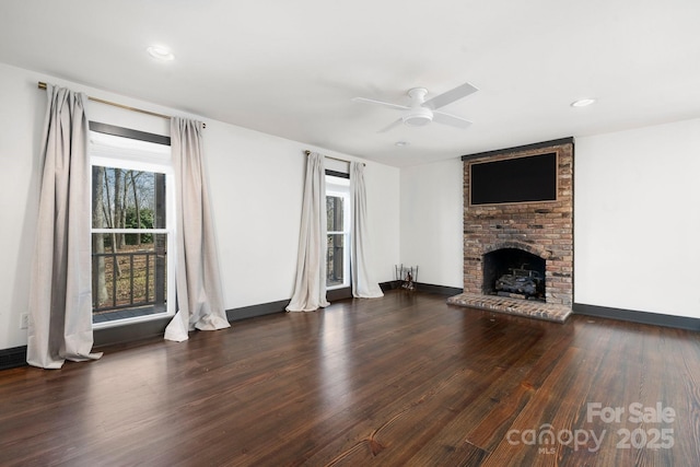 unfurnished living room featuring baseboards, dark wood-style floors, a brick fireplace, a ceiling fan, and recessed lighting