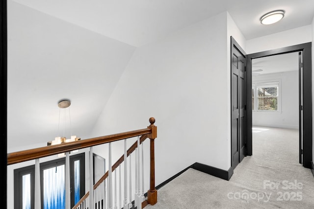 hall with baseboards, light carpet, and an upstairs landing