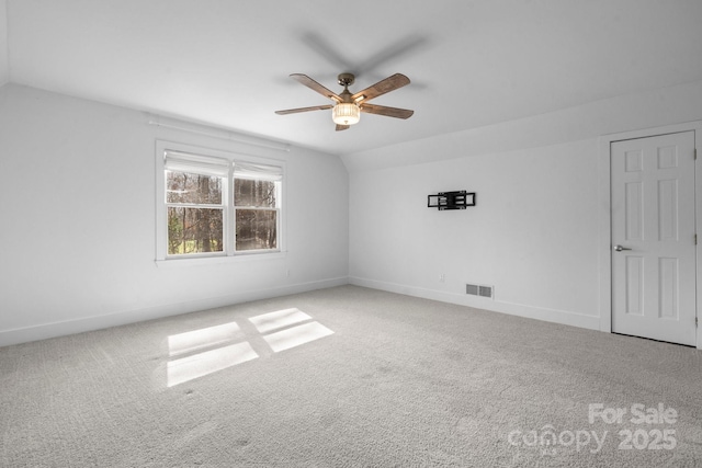 spare room featuring a ceiling fan, baseboards, visible vents, lofted ceiling, and carpet floors